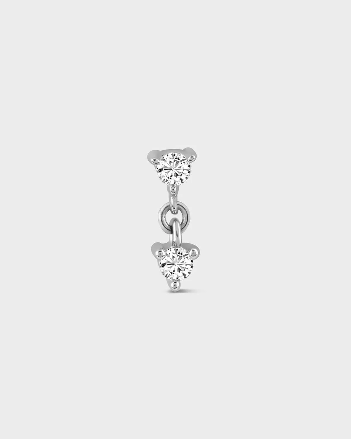 Silver earring with two clear gemstones on a light gray background