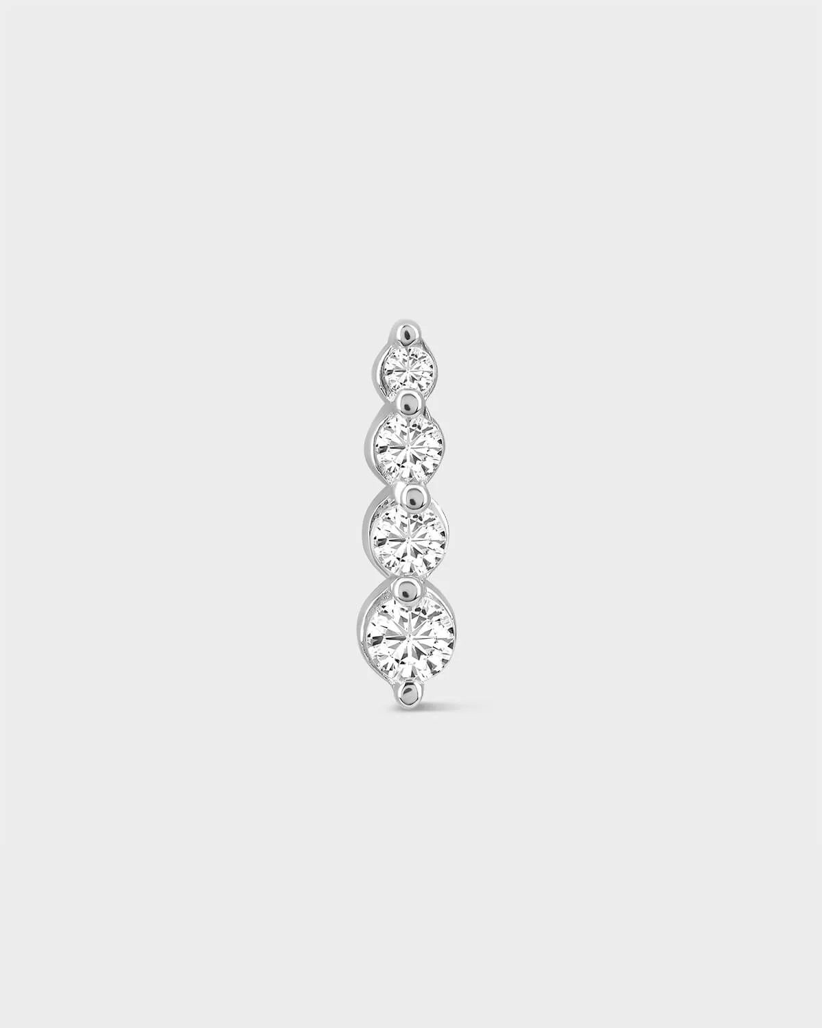 Silver earring with four clear gemstones on a light gray background