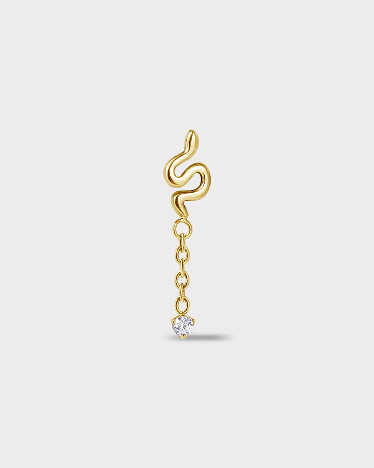 Gold titanium earring with a snake-shaped top and a short chain detail, finished with a clear round-cut gem on a light gray background.