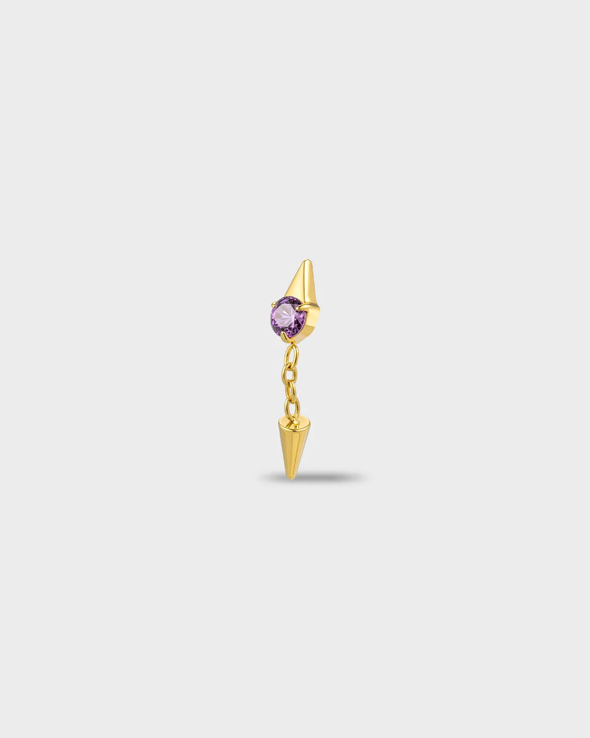 Gold titanium earring with a round-cut amethyst purple stone and a short chain dangle finished with a polished spike, on a light gray background.