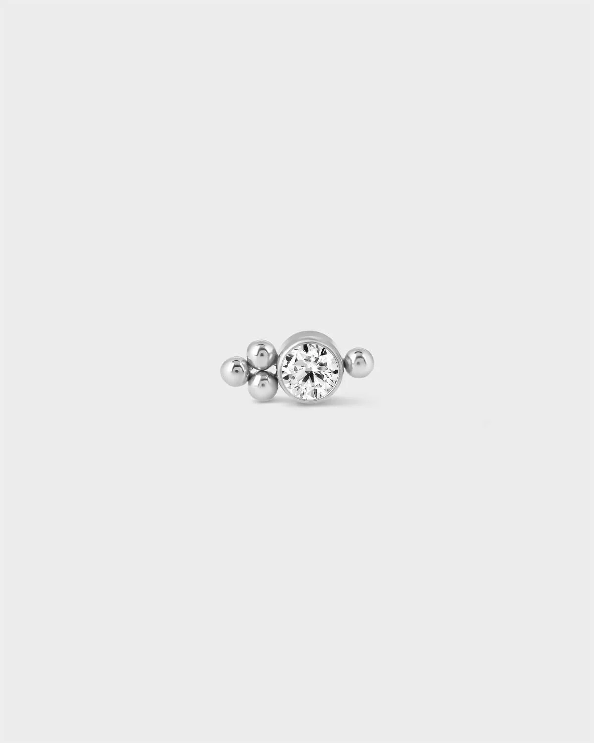 Polished titanium bezel set gem earring with 1 decorative bead to one side and 3 beads to the opposite side on a light greay background.