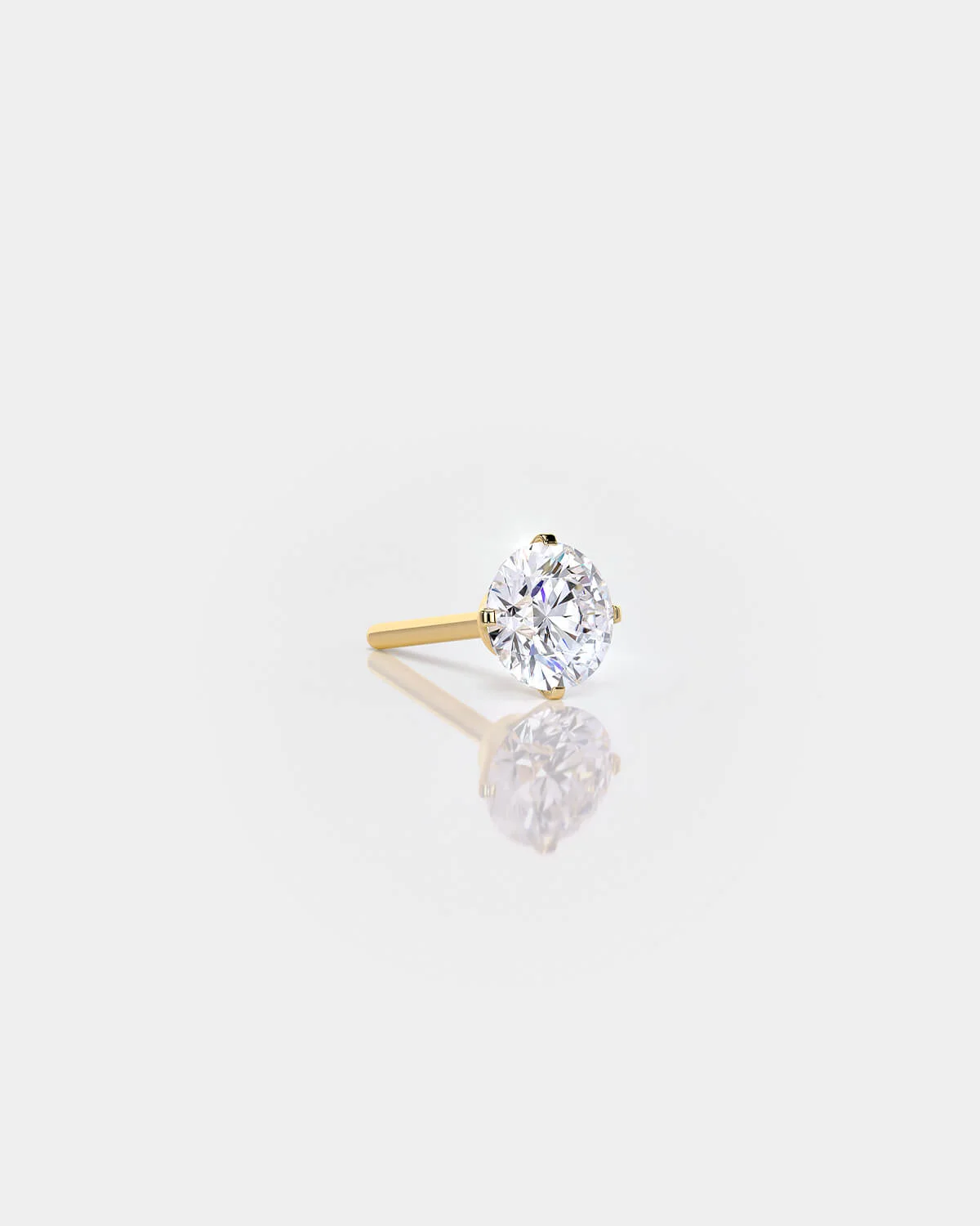 Gold earring with a clear gemstone on a light gray background