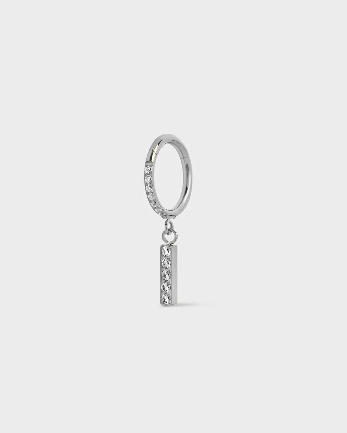 Polished silver titanium ring with pavé set gems along the front edge, finished with a vertical bar drop accented by a row of matching pavé stones. On a light gray background.