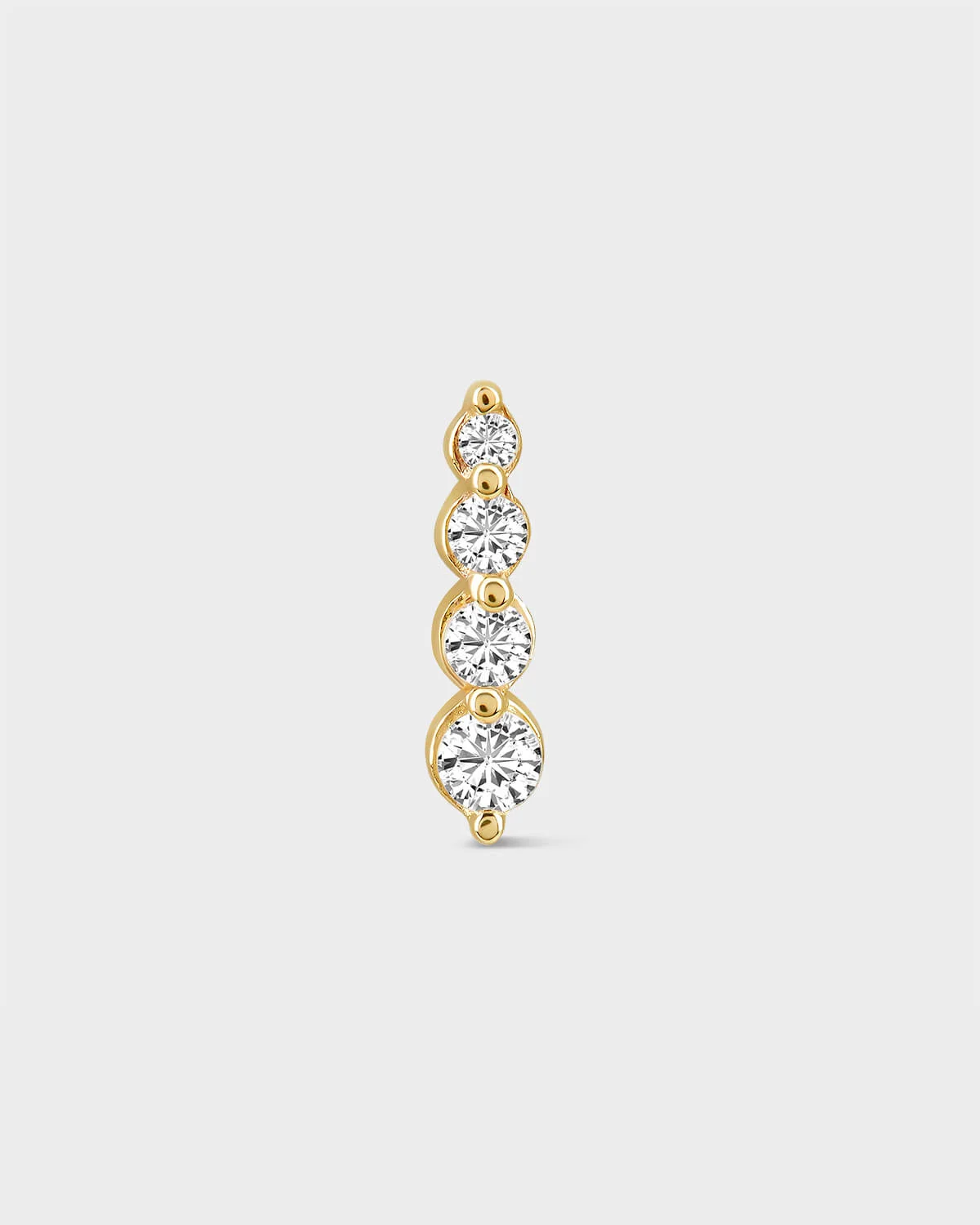Gold earring with four clear gemstones on a light gray background
