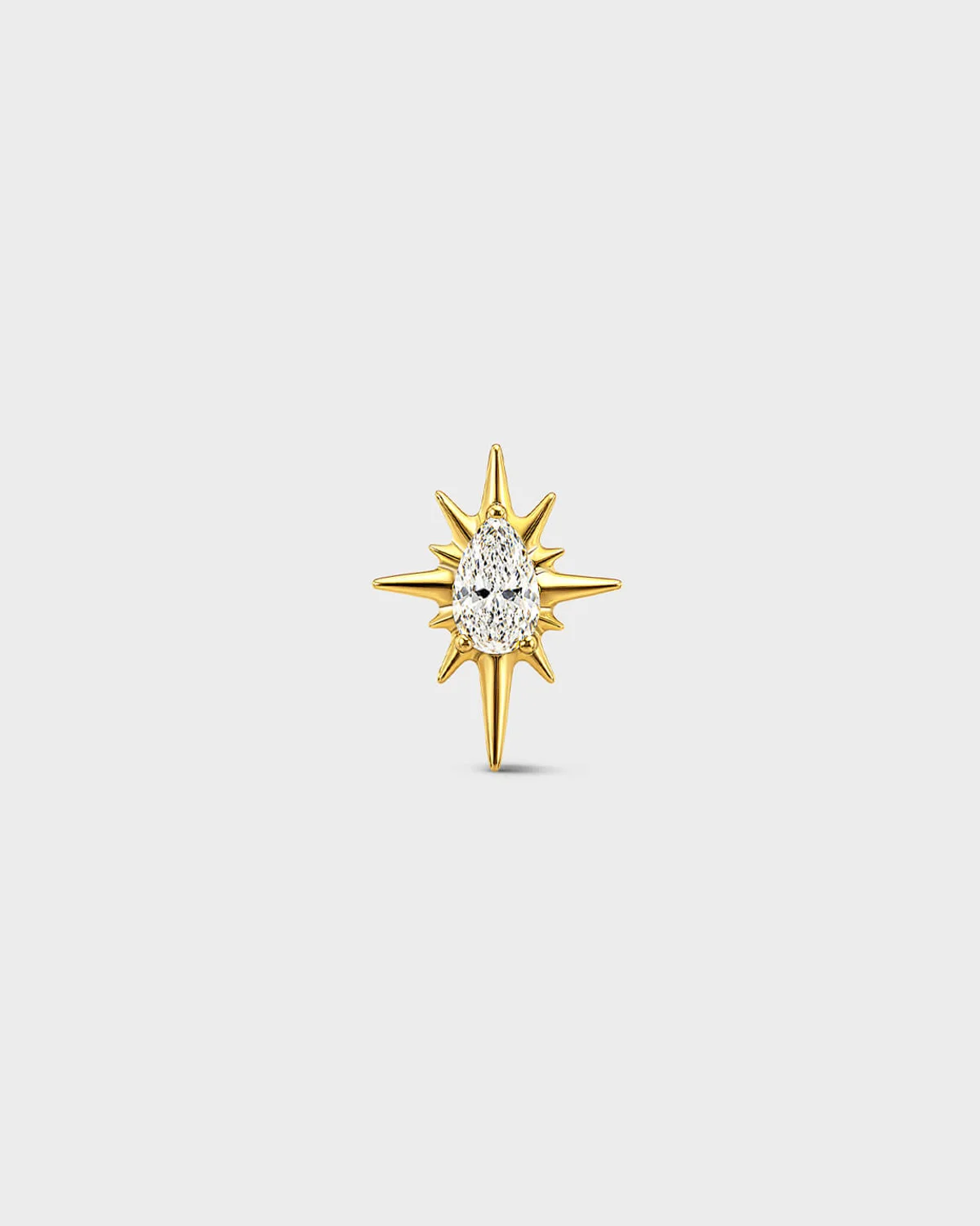 Gold titanium threadless end with a marquise-cut clear stone set within a sculpted starburst design. On a light grey background.