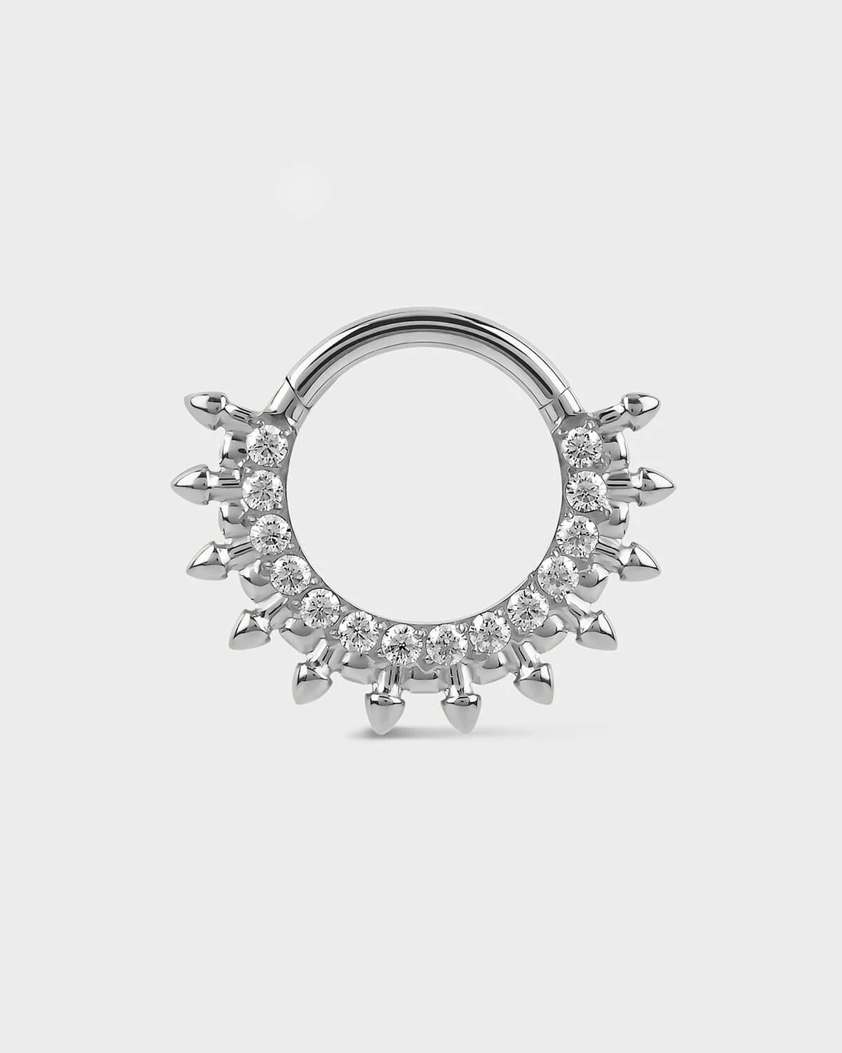 Polished titanium septum daith ring with diamond-like stones on a light gray background
