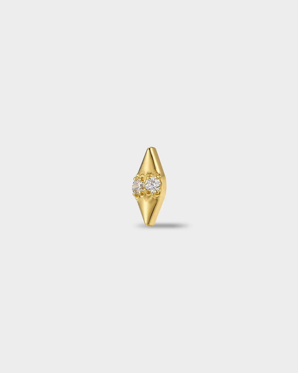 Gold titanium earring with two round-cut clear stones set into a smooth, tapered base, on a light gray background.