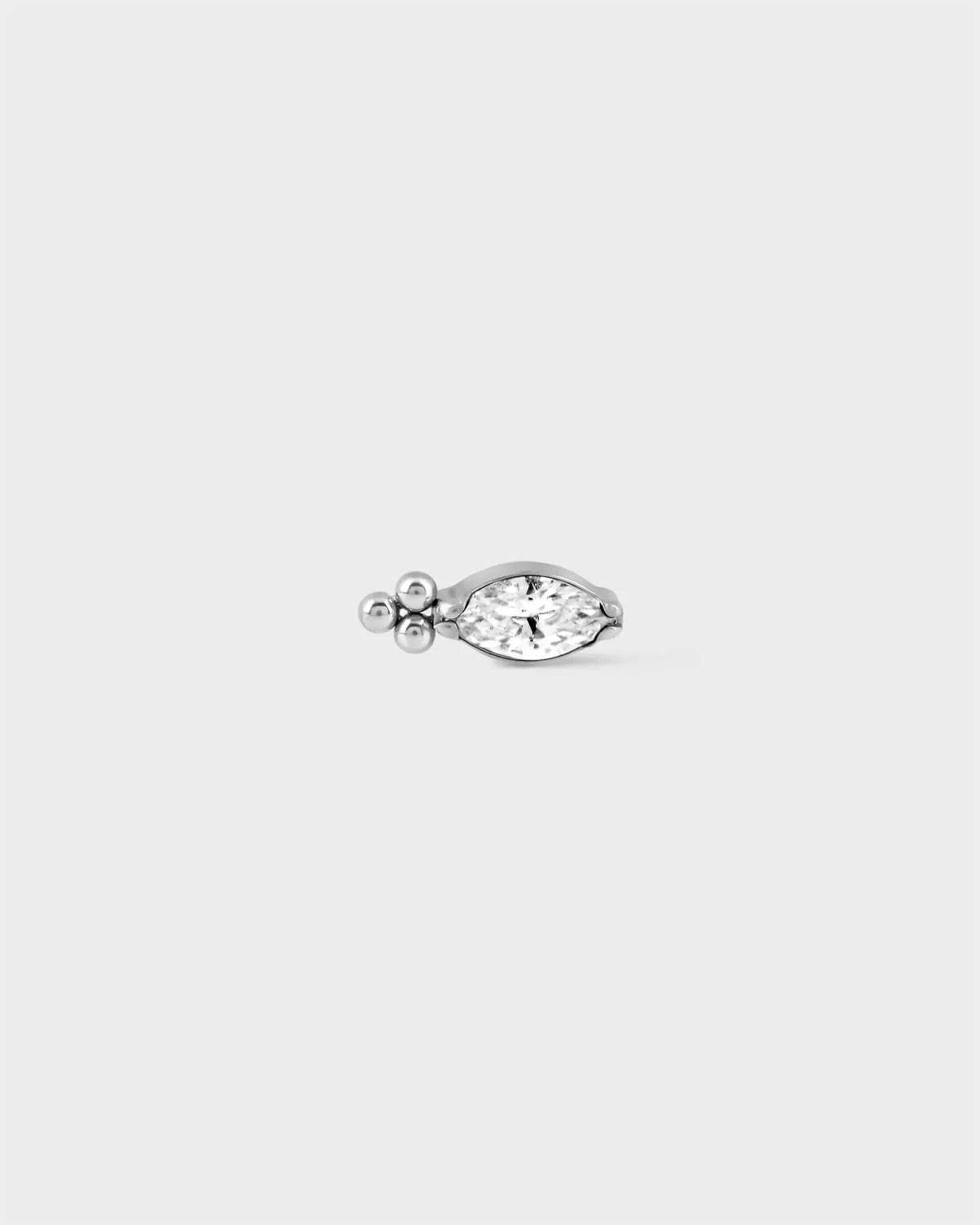 Polished titanium earring with marquise gemstone and three decorative beads to one end on a light grey background.