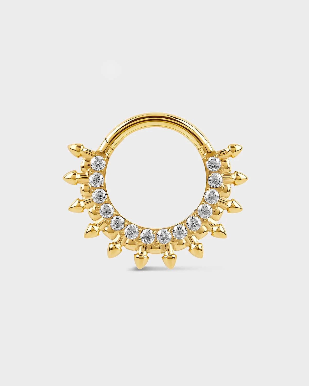 Gold septum daith ring with diamond-like stones on a light gray background