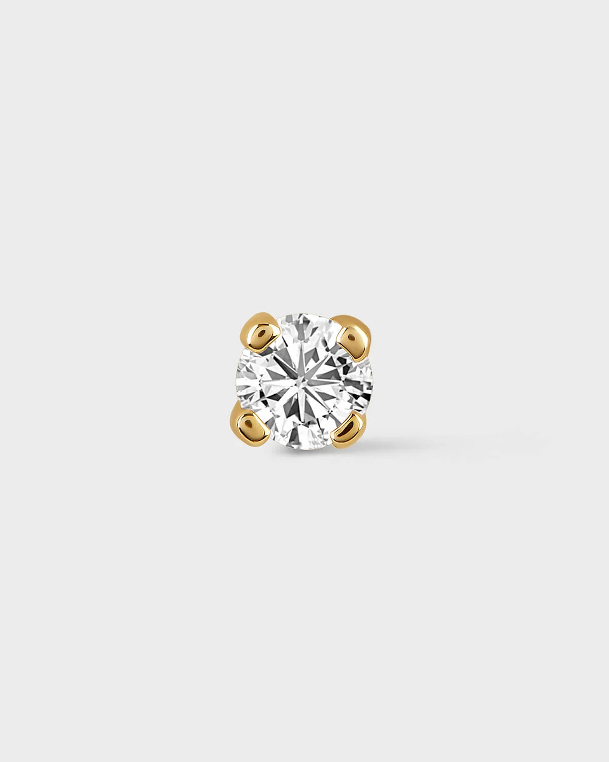 Single diamond earring on a light gray background