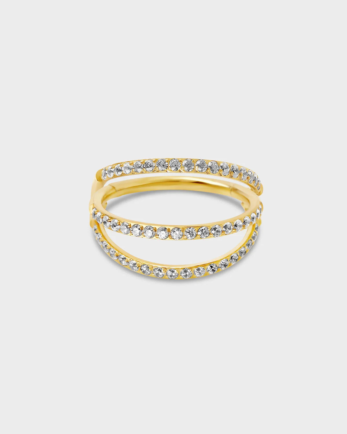 Gold titanium triple stack pave ring with clear gemstones on a light gray background.