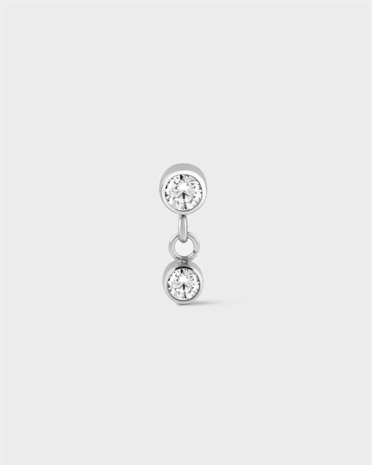Polished titanium bezel set solitaire earring with a second smaller bezel set solitaire drop with ring connector on a light grey background.