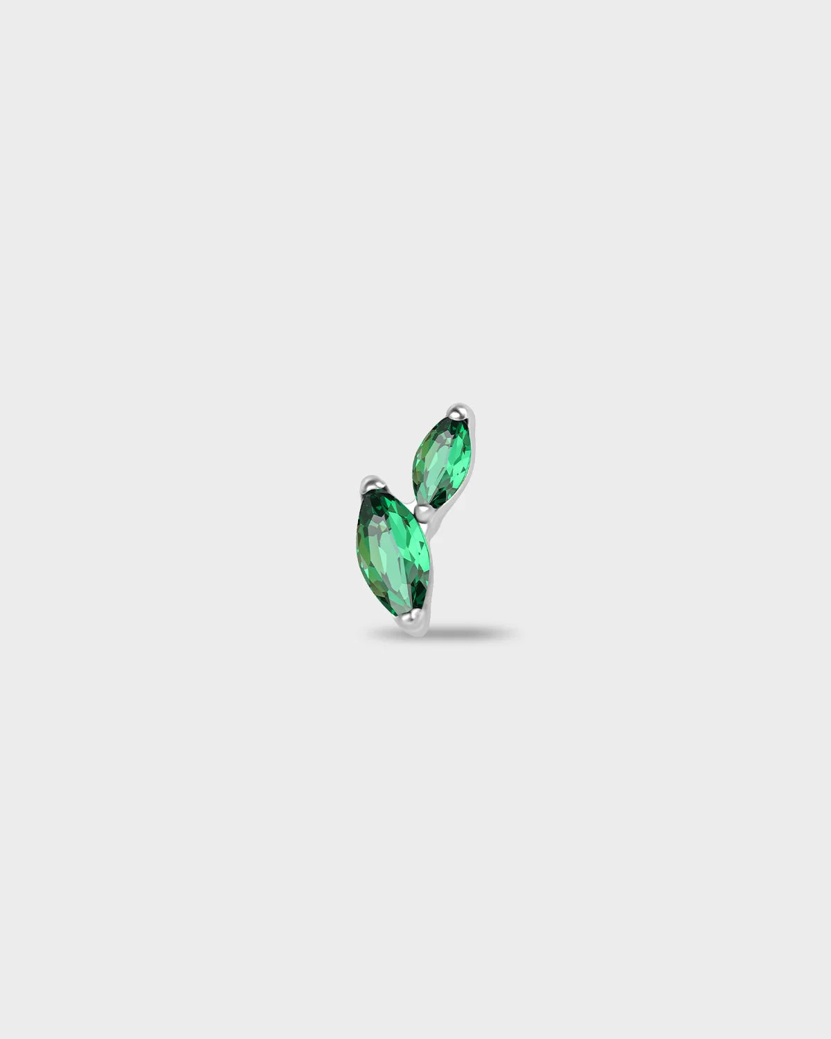 Polished silver titanium earring with two marquise-cut emerald green stones set in a curved vertical arrangement on a light gray background.