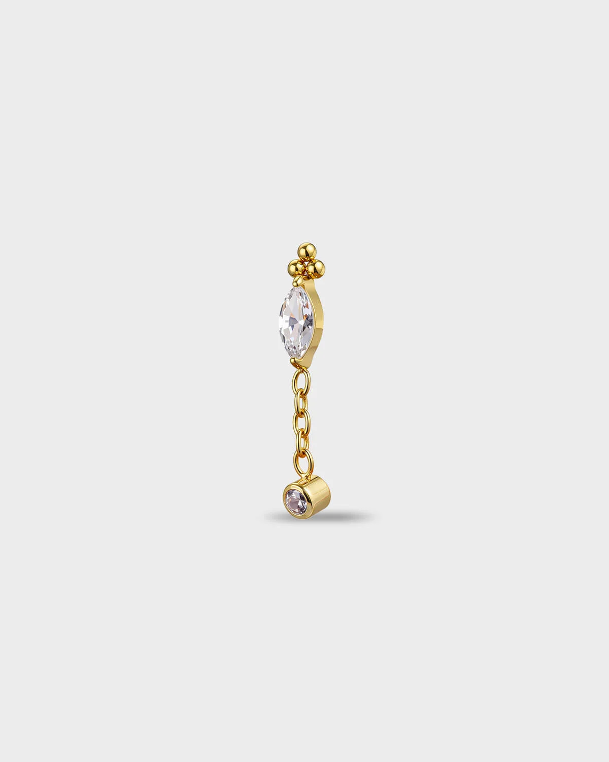 Gold titanium earring with a marquise-cut clear stone, a short chain dangle, and a small round-cut clear stone in a bezel setting, on a light gray background.