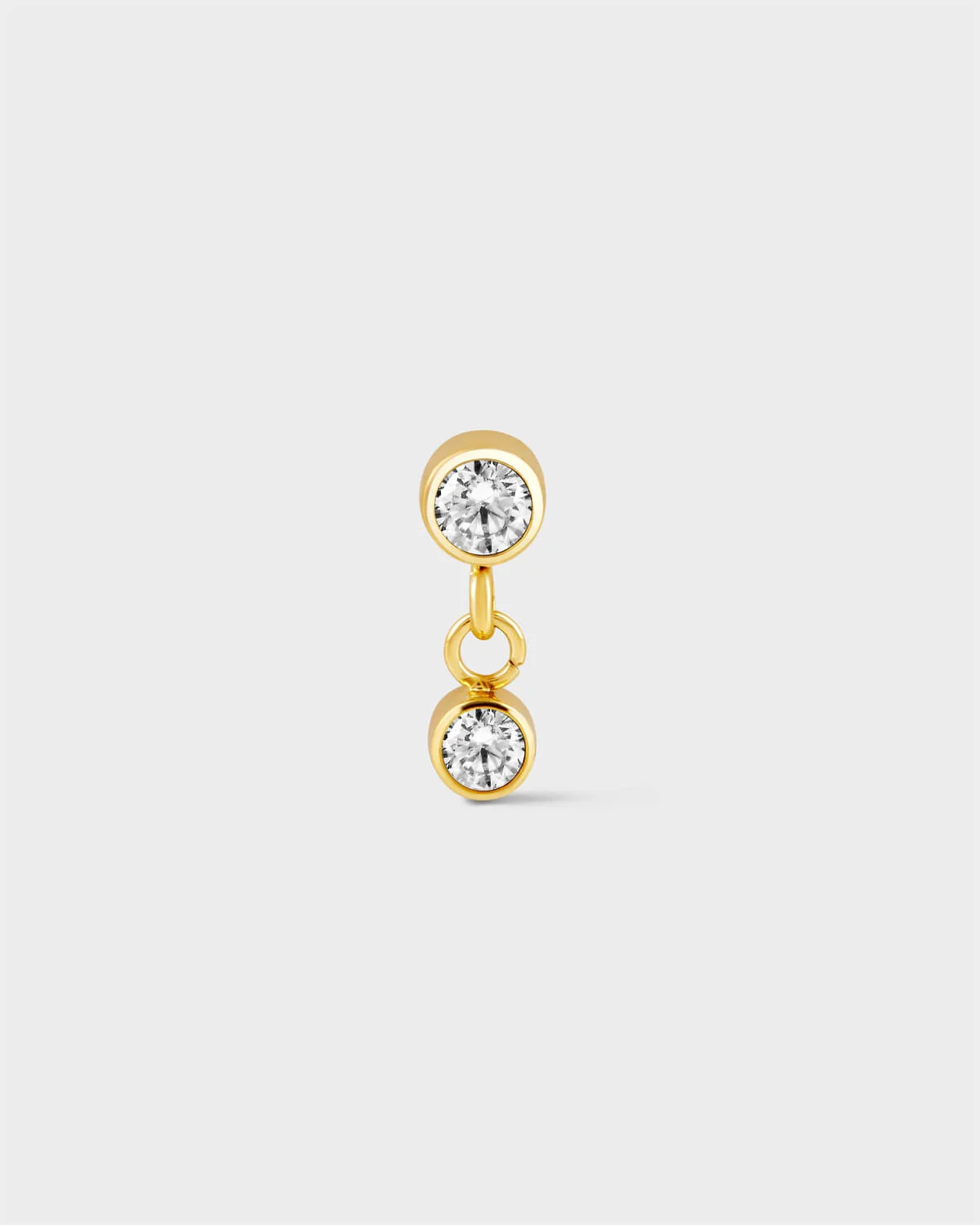 24k Gold titanium bezel set solitaire earring with a second smaller bezel set solitaire drop with ring connector on a light grey background.
