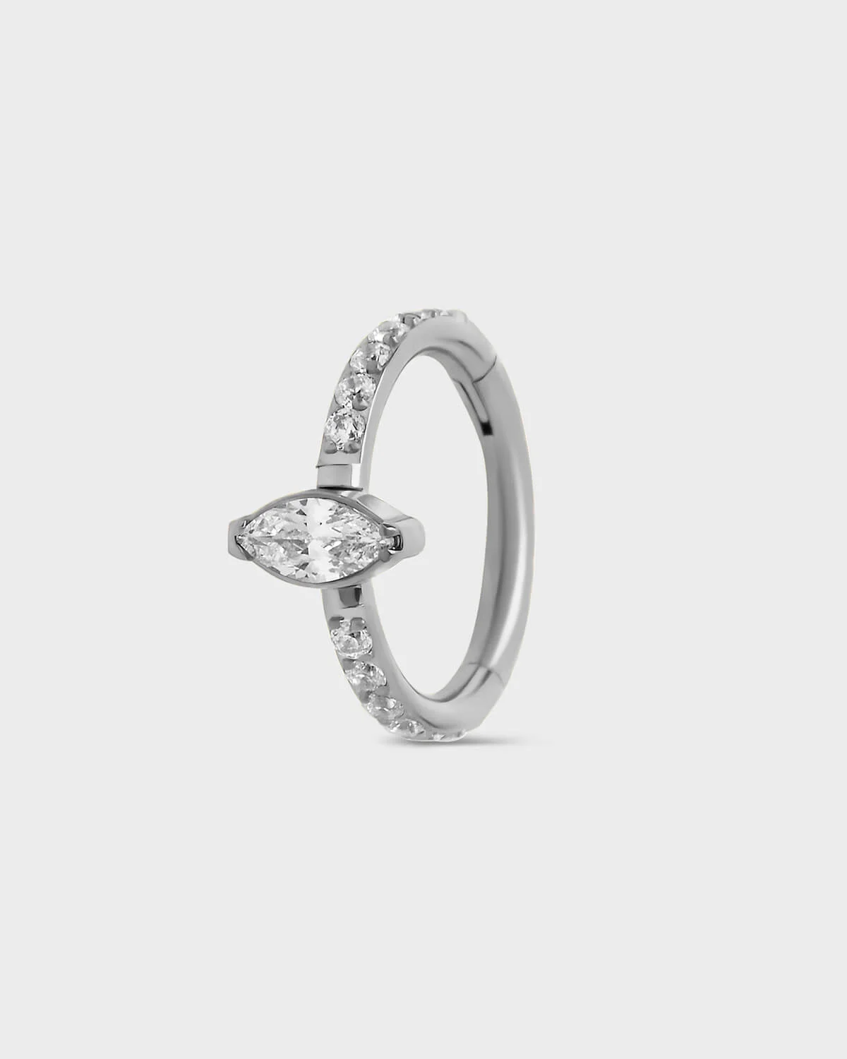Polished silver titanium pave hinged ring with central marquise gem sat on a light gray backround.