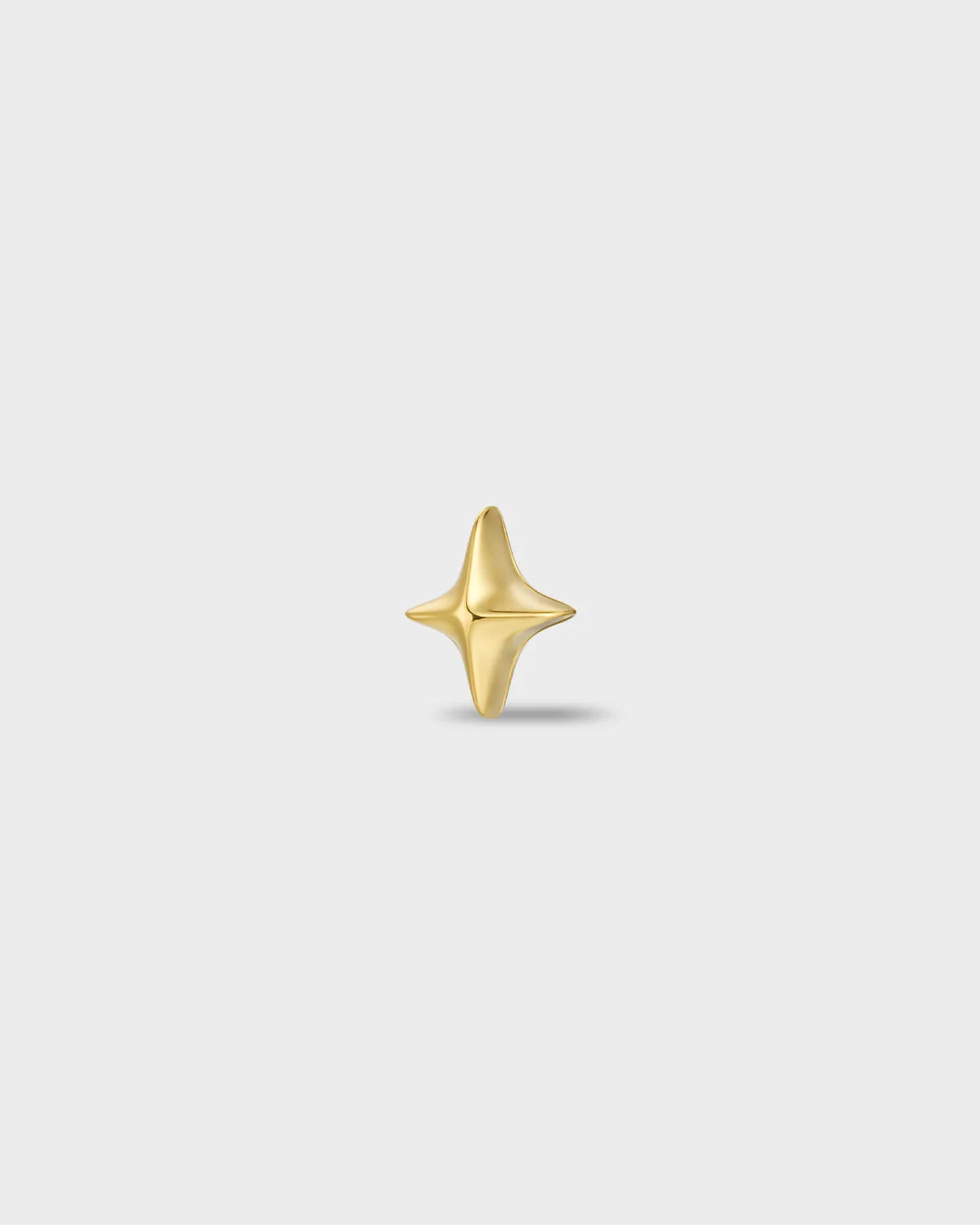 Gold titanium earring with a polished four-point star shape on a light gray background.