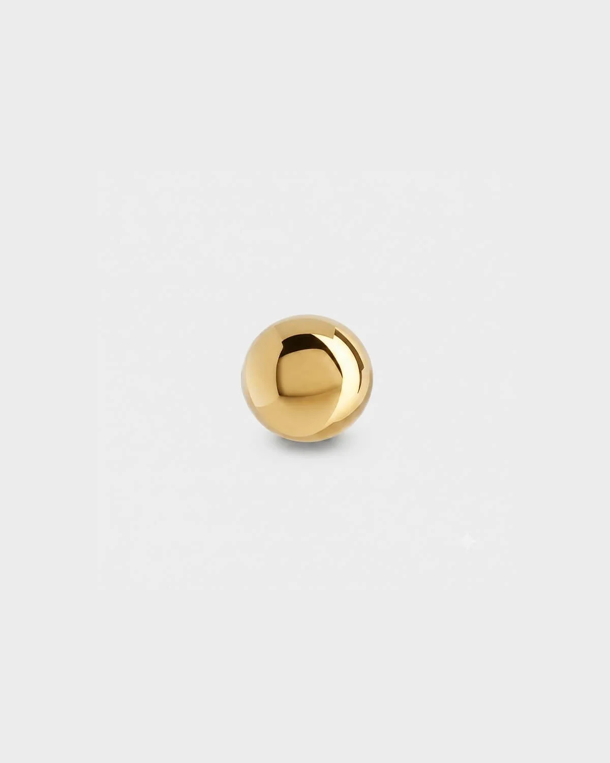 Plain gold titanium ball for piercing jewellery on a light grey background