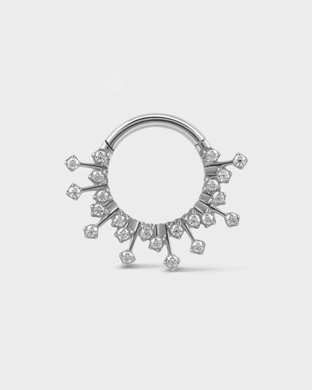 Polished silver titanium daith septum ring with small gramstones on a light gray background