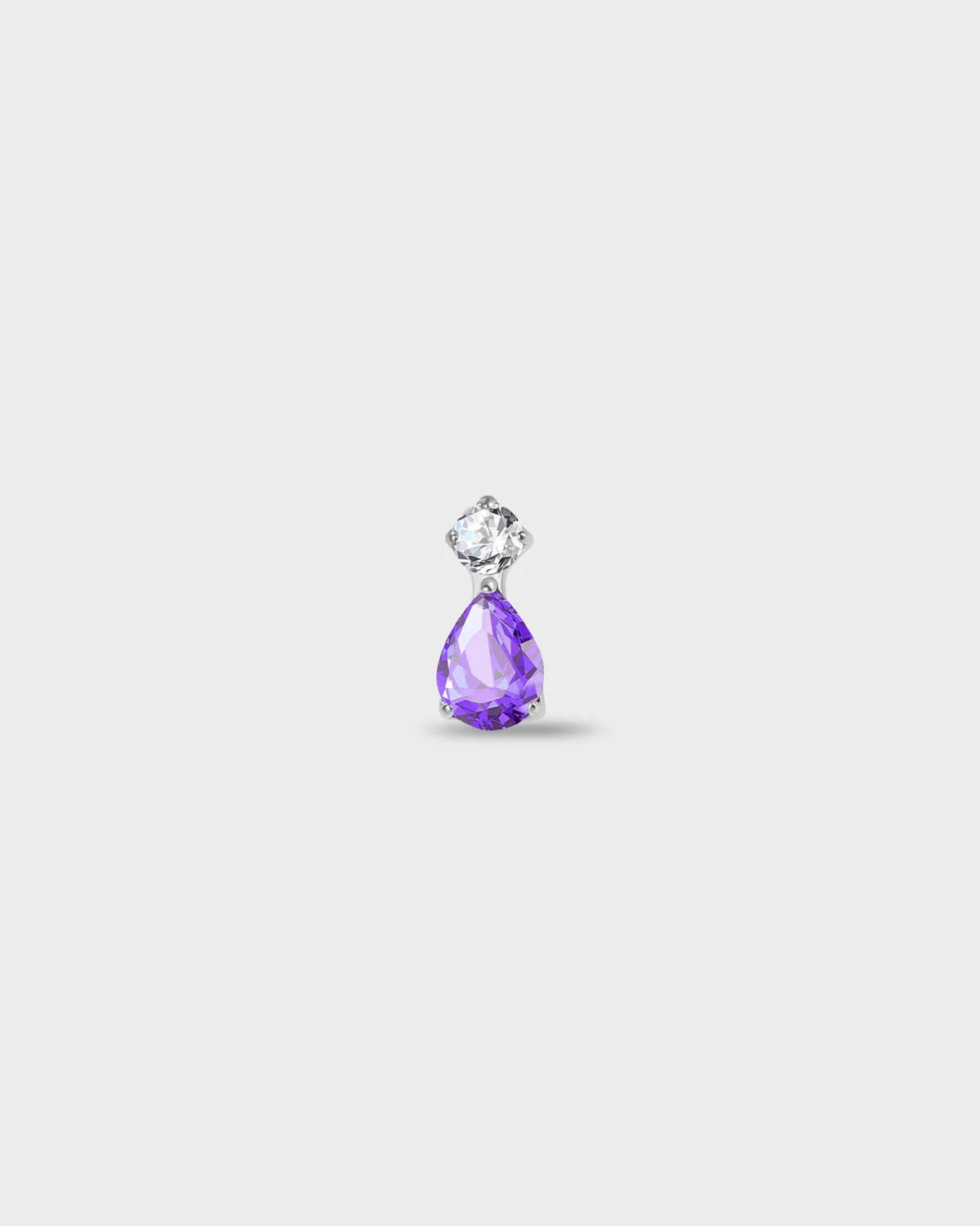 Polished silver titanium earring with a round-cut clear stone set above a pear-cut amethyst purple stone on a light gray background.