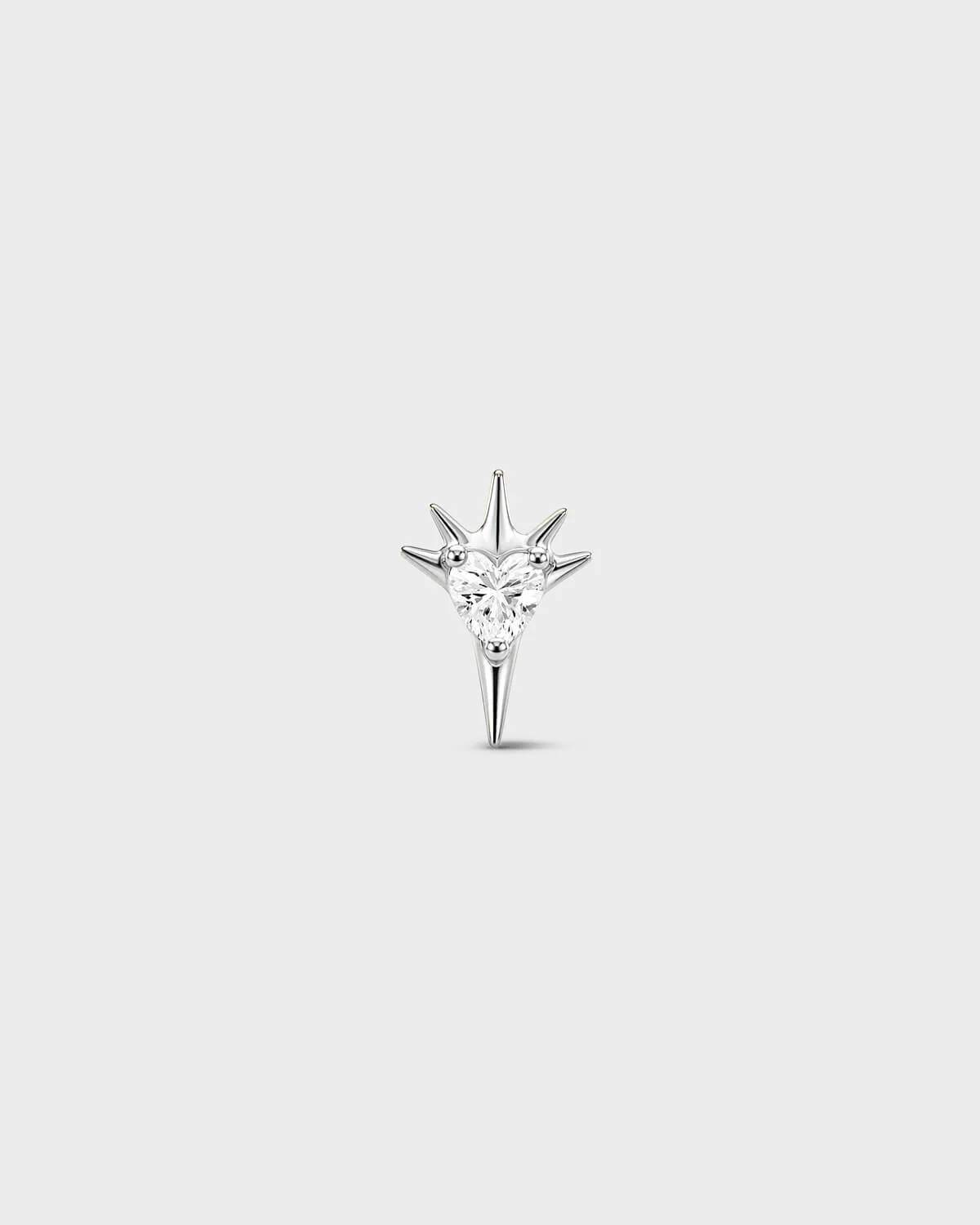 Polished silver titanium threadless end earring with a heart-cut clear stone set within a sculpted starburst design. On a light grey background.