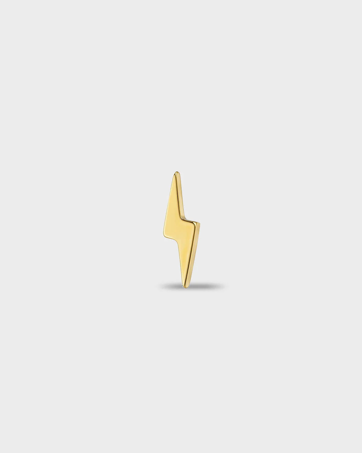 Gold titanium earring with a polished lightning bolt shape, on a light gray background.