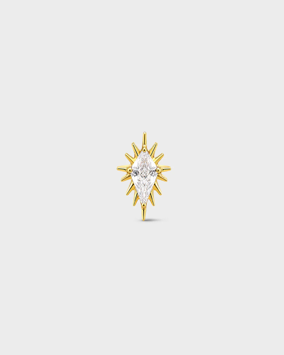 gold titanium threadless end earring with a marquise-cut clear stone set within a sculpted starburst design. On a light grey background.