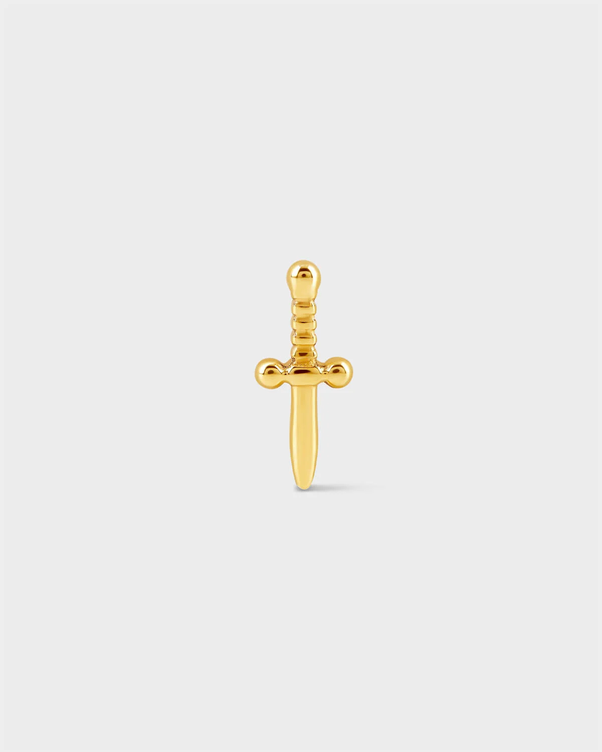 Gold titanium dagger style earring on a light grey background