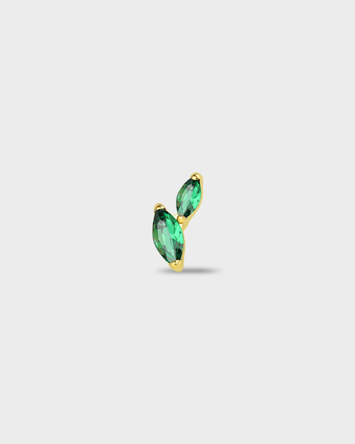 Gold titanium earring with two marquise-cut emerald green stones set in a curved vertical arrangement on a light gray background.