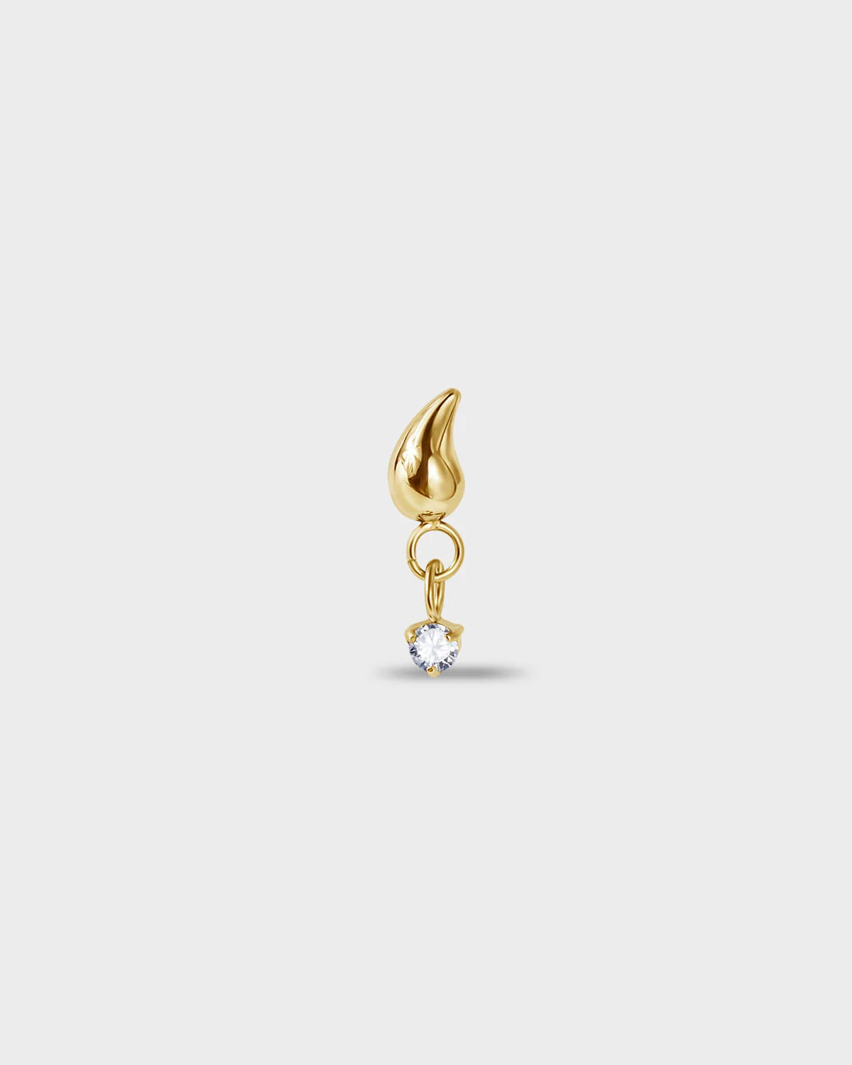 Gold PVD titanium earring with a tear drop shape at the top and a suspended clear solitaire dangle on a light gray background