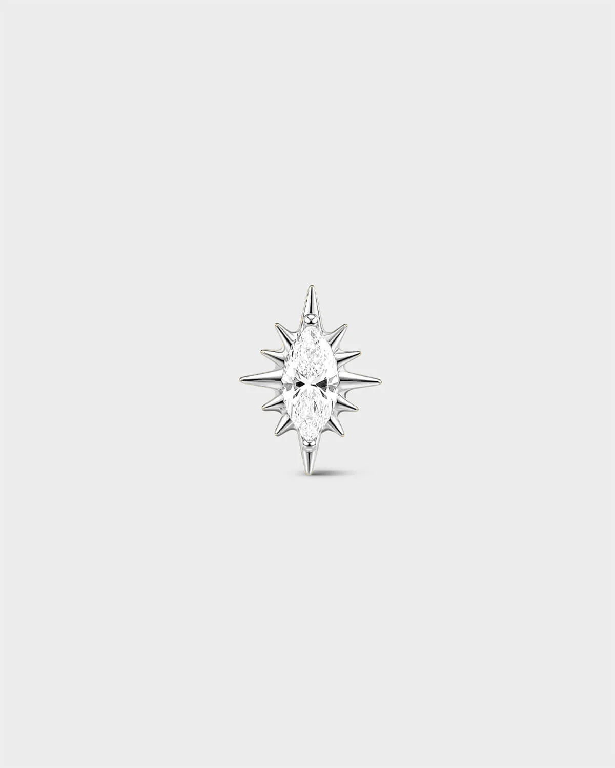 Polished silver titanium threadless end earring with a marquise-cut clear stone set within a sculpted starburst design. On a light grey background.
