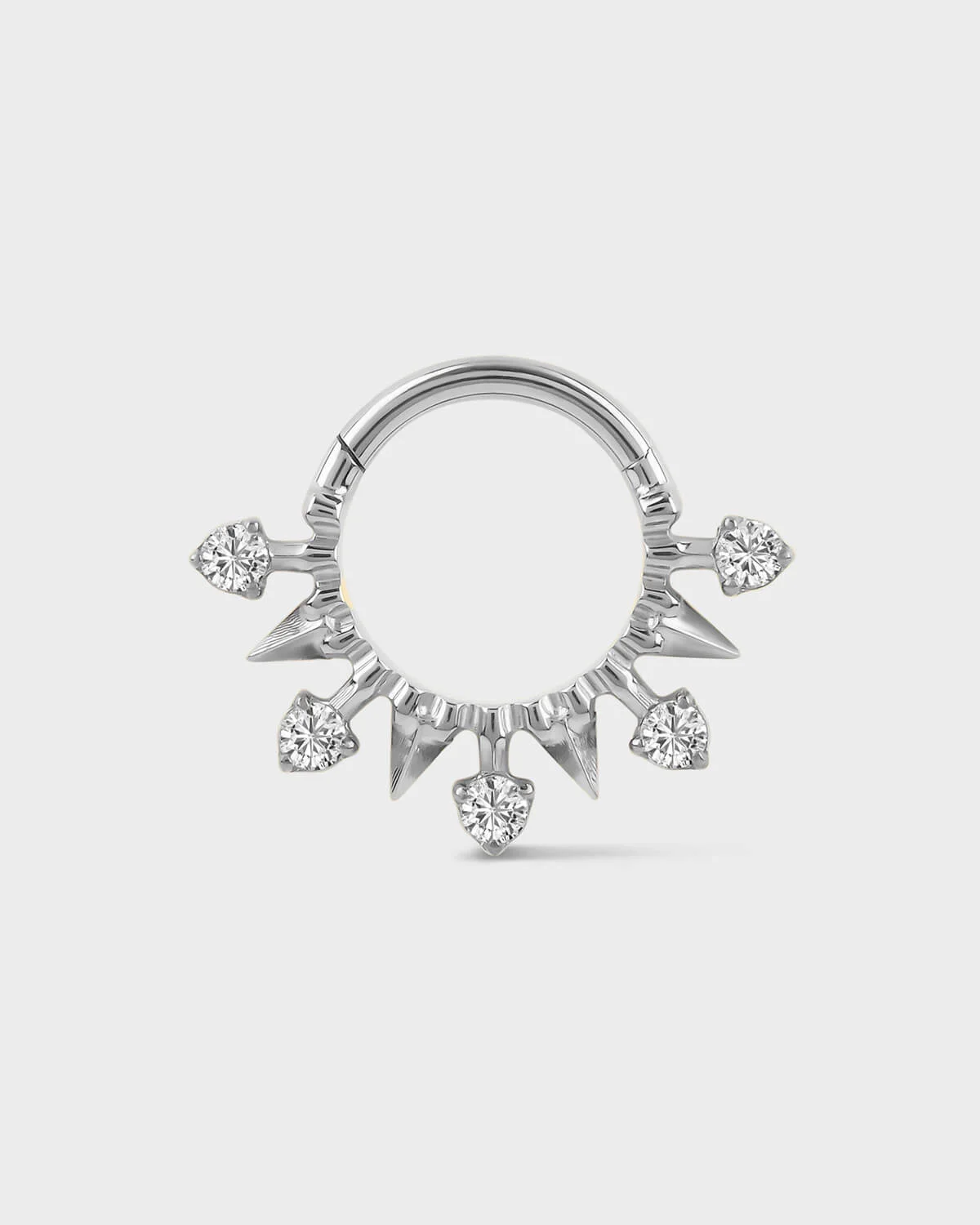Polished silver titanium daith or septum ring with alternating spikes and solitaires on a light gray background.