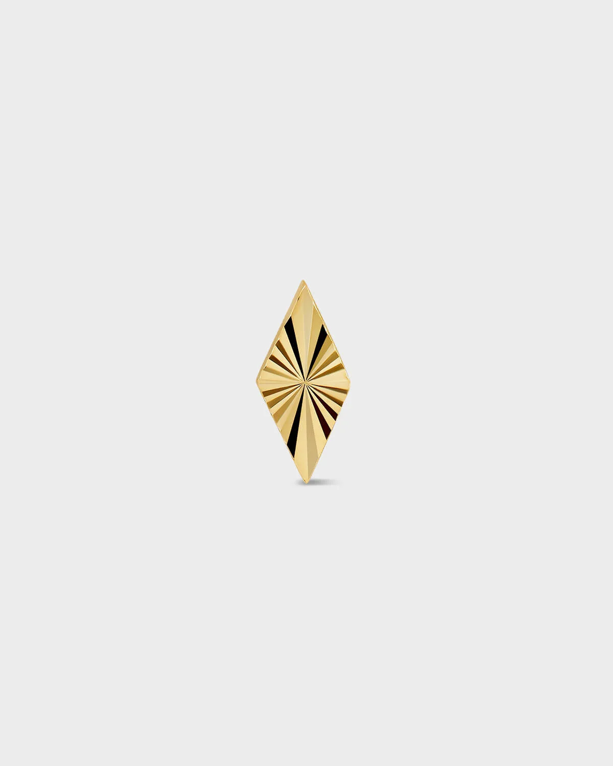 Diamond shape gold earring with laser engraved lines on a light ray background