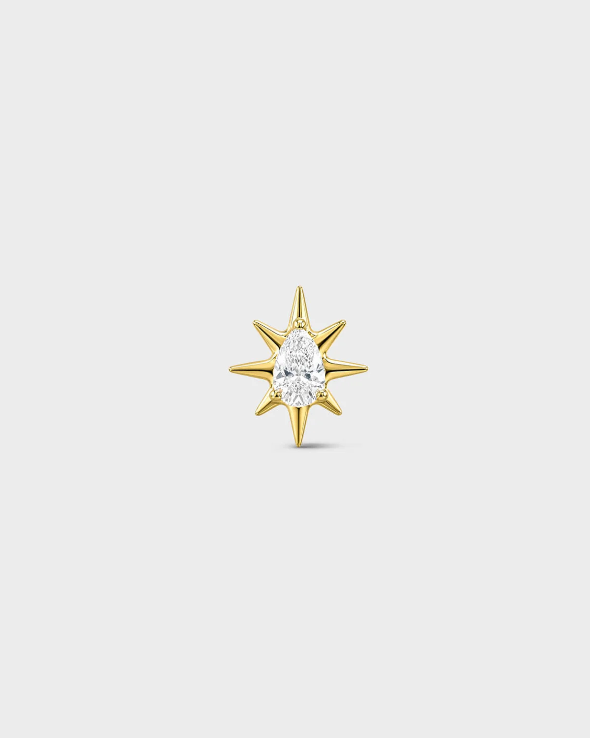 Gold titanium threadless end with a marquise-cut clear stone set within a sculpted starburst design. On a light grey background.